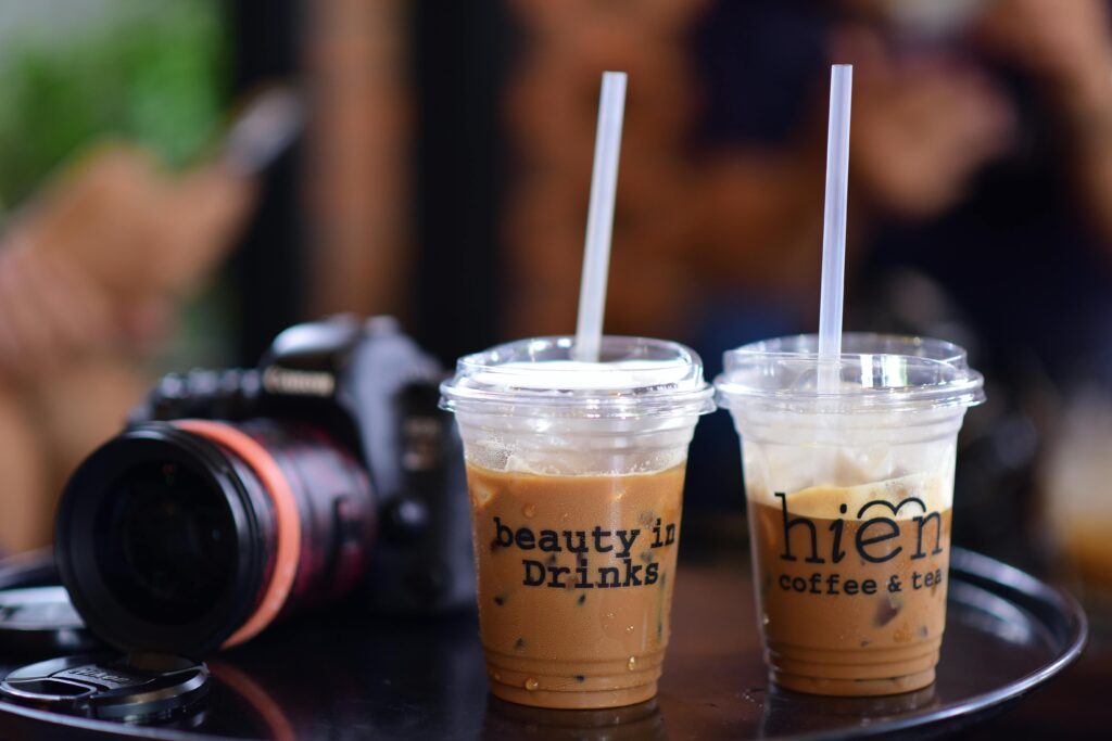 Close-up of iced coffee drinks beside a camera on a table, suggesting a relaxing café scene.